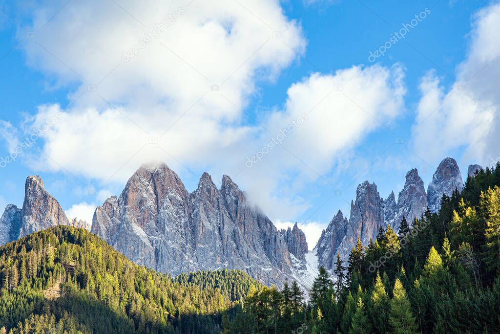  Dolomites on a sunny autumn day. Lush clouds lit by the setting sun. South Tyrol. The majestic cliffs of the Dolomites rise picturesquely into the sky.