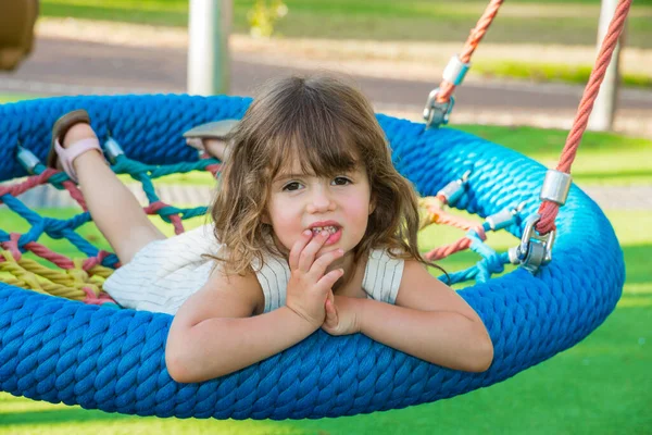 長い髪の美しい小さな女の子が喜んで子供のスイングに振れる 子供公園の暖かい夏の日 — ストック写真