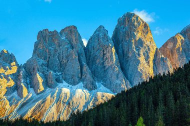 Dolomitlerin görkemli kayalıkları gökyüzüne doğru yükseliyor. Güneşli bir sonbahar gününde Dolomitler. Batan güneşin aydınlattığı bulutlar. Güney Tyrol. 