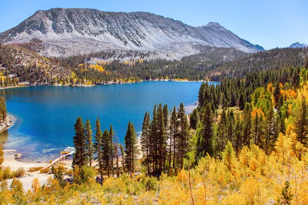 Rock Creek Yolu. Montana, ABD 'de bereketli bir sonbahar. Mavi sularla çevrili muhteşem oval göl resimsi dağlar ve kozalaklı ve yaprak döken ormanlarla çevrilidir.