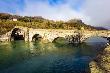 Italy, Lucca. The emerald cold water of the river reflects the ancient asymmetrical arches of the bridge. The bridge of Mary Magdalene is medieval structure that crosses the Serchio River. 