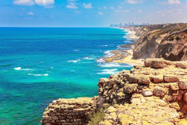 Mediterranean coast. Sea surf with white foam of waves. Picturesque ruins of the medieval citadel of Arsuf. Apollonia Park, Israel