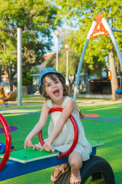 ブロンドの髪にパナマの魅力的な女の子は 単に子供のスイングで笑う 遊び場での暖かい夏の日 — ストック写真