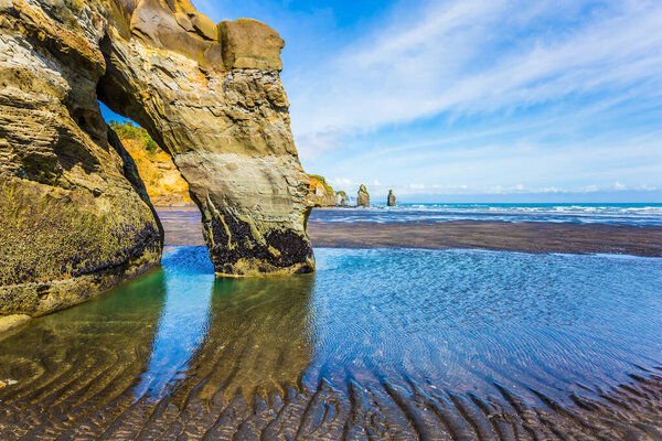 Coastal rock arches  "Three Sisters" and "Elephant" on the Pacific coast. The concept of active and phototourism. New Zealand, North Island