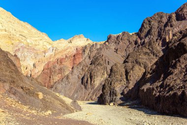 Sıcak Kasım günü. Renkli peyzaj oluşumları. Taş çölün geçidinde toprak yol. Eilat Dağları. İsrail dağlarındaki yıpranmış kumtaşı.