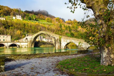 Magdalalı Meryem 'in köprüsü Serchio Nehri' ni geçen ortaçağ yapısıdır. İtalya, Toskana vilayeti. Nehrin yeşil soğuk suyu eski asimetrik kemerleri yansıtır..