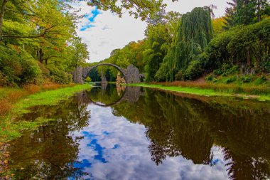  Eşsiz mimari anıt Rakots Nehri üzerindeki Şeytan Köprüsü 'dür. Park Kromlau, Almanya. Köprünün bazalt sütunları sudaki yansımalarıyla mükemmel bir daire oluşturur.