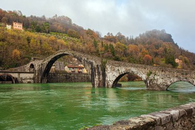 Sercchio Nehri 'nin soğuk yeşil suları. İtalya. Toskana vilayeti. Lucca şehrinin yakınlarında, Ponte della Maddalena Köprüsü. Köprü bin yıl önce yapıldı. Soğuk rüzgarlı kış günü
