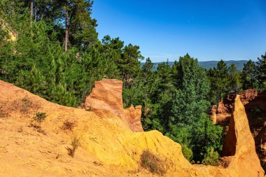 Şimdi kayalar sık ormanlara dönüştü. Roussillon köyü. Garip Ocher kayaları. Fransa, Provence. En güzel kırmızı-sarı-turuncu yol boyunca yürü.