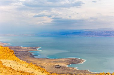 The great wonder of nature is the Dead Sea. Cloudy and clear January day. The sea surface reflects the clouds. Israeli coast. Jordan on the opposite coast of the sea 