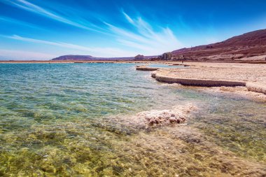 Suyun yüzeyinde, buharlaşmış tuz tuhaf kristal şekiller oluşturur. Eşsiz Ölü Deniz. Sıcak kış şubat ayı. İsrail 'deki kurumuş tuz gölü, dünyanın en tuzlu gölü.. 