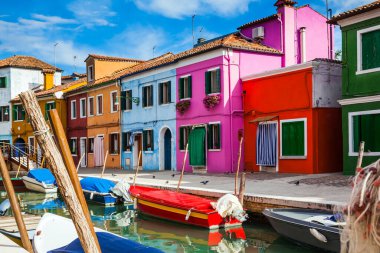 Venedik yakınlarındaki Burano adası. Sabah güneşiyle aydınlatılan parlak renkli binalar. Tekneler kanalların kıyıları boyunca park halindedir. Kültür, tarih ve fotoğraf turizmi kavramı