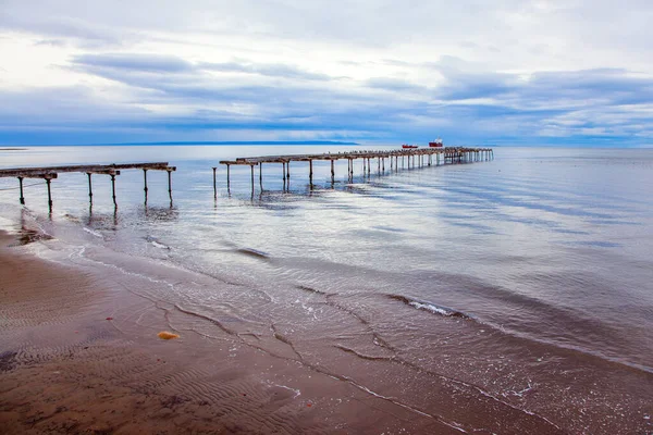 Punta Arenas 'taki harabe okyanus iskelesi. Macellan Boğazı. Meşhur Tierra del Fuego ufukta görünüyor. Gökyüzü ağır gök gürültülü bulutlarla kaplıdır.
