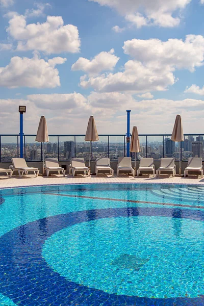 高層ホテルの屋上プール プールの周りでは サンラウンジャーがお客様を待っています イスラエルのテルアビブだ プールの丸いボウルは清潔で透明な水で満たされています — ストック写真