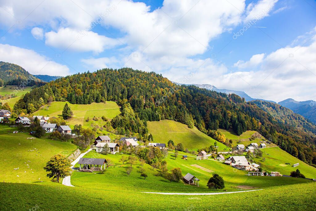 Small village in mountain valley. Picturesque Julian Alps. Beautiful autumn day. Charming pastoral. Green grassy lawns in a mountain valley. Travel to Slovenia. 