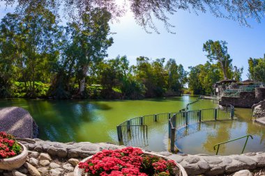  Ürdün Nehri. Nehir kıyısı ağaçlarla ve çiçeklerle süslenmiştir. Yardenit, İsrail. Sembolik vaftiz töreninin yapıldığı yer. Dini ve fotoğraf turizmi kavramı