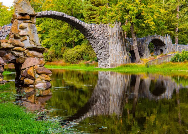 The Devil\'s Bridge,  Park Kromlau, Germany. The basalt columns of the bridge reflection in the water. Unique architectural monument is the Devil\'s Bridge on the Rakots River.