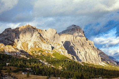  Gray and white dolomite rocks. The clouds are flying across the sky. The majestic pass in the Eastern Alps of Falzarego. Picturesque sunset in the colorful rocks of the Dolomites. 