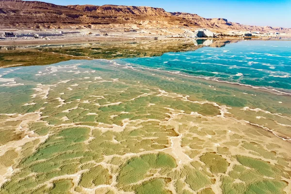 Dead Sea. Evaporated salt forms bizarre patterns on the water. The green water is surrounded by pink mountains. Sunny winter day. The picture was taken by a drone from a aerial view. Israel. 