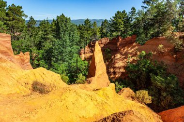 Now the rocks have grown into dense forests. The village of Roussillon is surrounded by picturesque ocher cliffs. Bizarre ocher rocks. France, Provence.