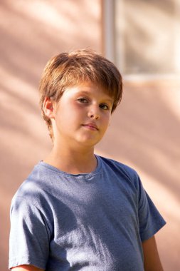 Warm spring day in a green park. Handsome boy with brown hair and green eyes, thoughtful