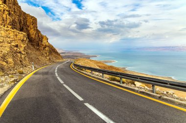 İsrail kıyıları. Otoyol Ölü Deniz kıyısı boyunca uzanıyor. Doğanın en büyük harikası Ölü Deniz 'dir. Deniz yüzeyi bulutları yansıtır. Bulutlu ve açık Ocak günü. 