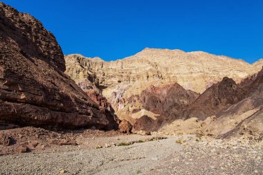  Taş çölün geçidinde toprak yol. Eilat Dağları. Sıcak Kasım günü. Renkli peyzaj oluşumları. İsrail dağlarındaki yıpranmış kumtaşı