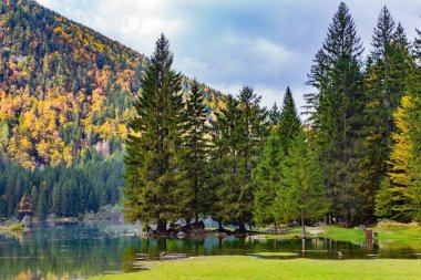 Öğlen. Dağ vadisindeki Lago Fuzine Gölü. Göl kıyılarını su basmış. Dağlar (sallanıp) kararıp döküldüğü zaman, İtalya 