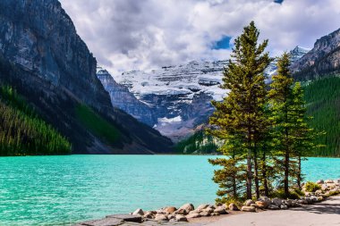 Banff 'taki Buzul Gölü Louise, Kanada Kayalıkları. Göl masmavi suyla çevrili dağlar ve ormanlarla çevrilidir. Güneşli güzel bir gün. Ekolojik, aktif ve fotoğraf turizmi kavramı