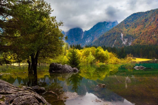 白云片上布满了云彩 意大利北部的富兹纳湖 秋天的绚丽色彩 橙色和黄色的树反映在绿油油的水中 — 图库照片