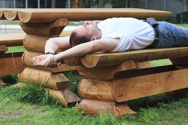 L'uomo dorme su una panchina di legno . — Foto Stock