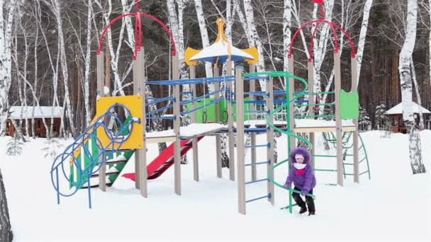 Little girl playing on the playground in winter. — Stock Video