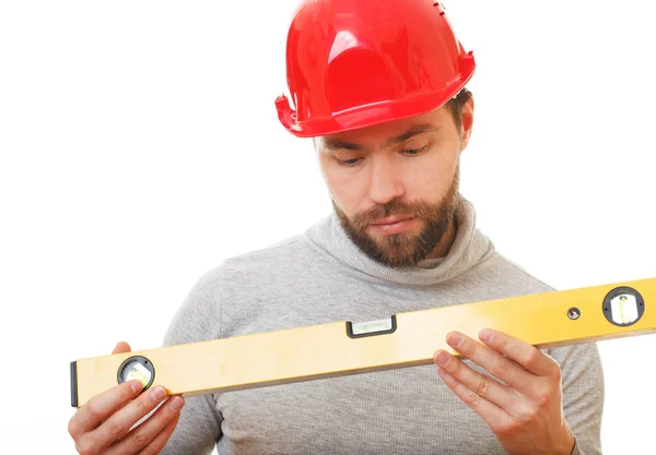 Trabalhador da construção em um capacete vermelho com um nível de mãos . — Fotografia de Stock