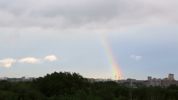 Nube gris cubre un arco iris sobre la ciudad. Vista del Timelapse — Vídeo de stock