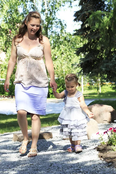 Beautiful pregnant woman with her little daughter walking — Stock Photo, Image