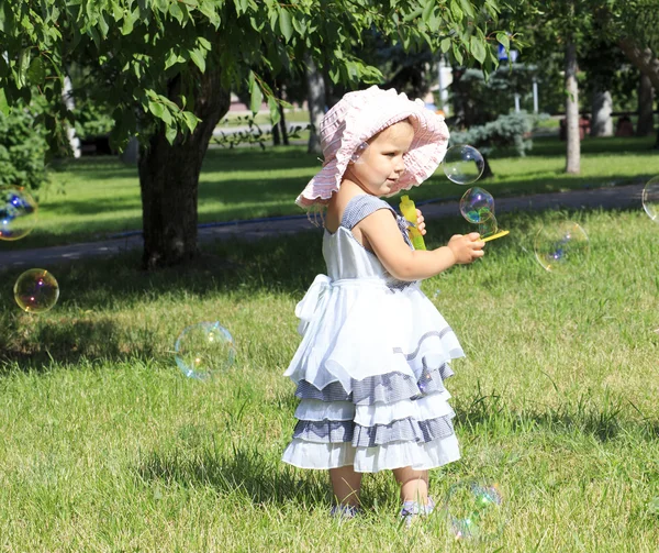 Little girl blowing soap bubbles in a city park. — Stock Photo, Image