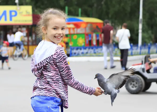 Vrolijk meisje met een duif op hand (voeden vogels zaden) — Stockfoto