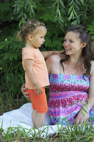 Beautiful pregnant woman talking with a young daughter. — Stock Photo, Image