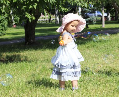 küçük kız bir şehir parkında sabun köpüğü üfleme.