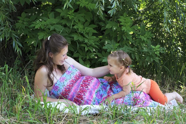 Vakre, gravide kvinner tar hånd om en liten datter. . – stockfoto