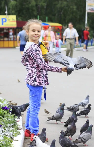 Freudiges kleines Mädchen mit einer Taube auf der Hand (Fütterung Vögel Samen) — Stockfoto