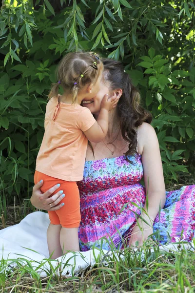 Menina ternamente beija e abraça sua mãe . — Fotografia de Stock