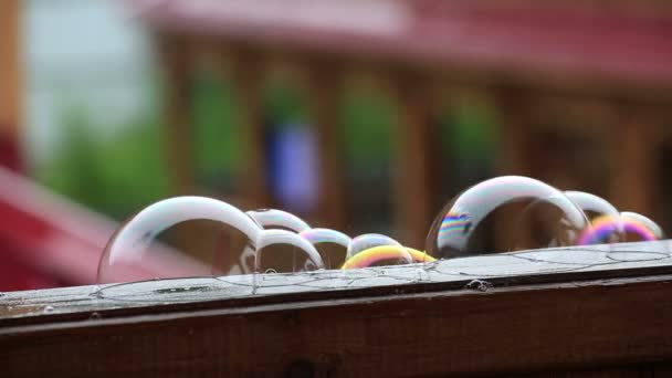 Zeepbellen op natte houten veranda leuning. — Stockvideo