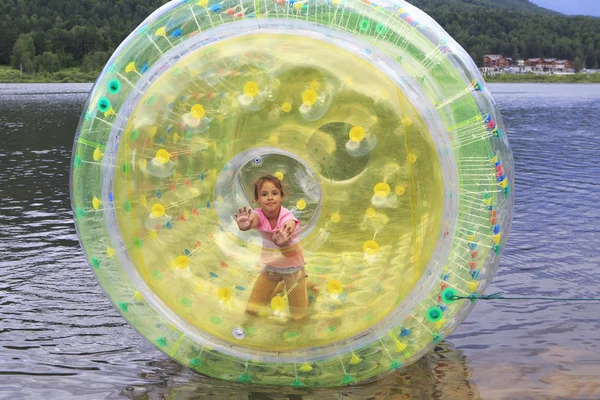 Criança na atração inflável no lago . — Fotografia de Stock