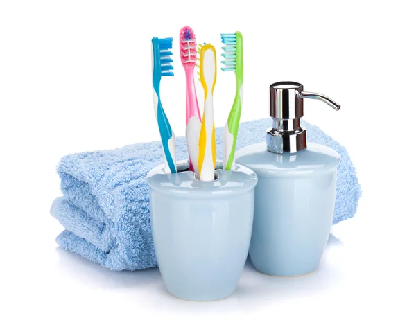 Four colorful toothbrushes, liquid soap and towel — Stock Photo, Image