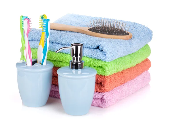 Vier tandenborstels, vloeibare zeep, haarborstel en kleurrijke handdoeken — Stockfoto
