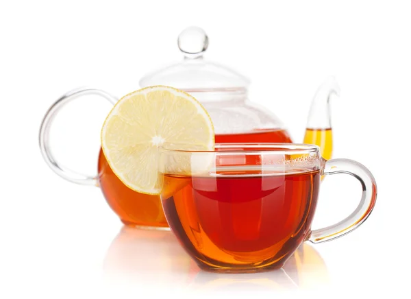 Copa de vidrio con rodaja de limón y tetera de té negro — Foto de Stock