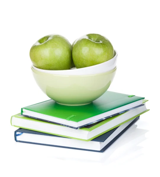 Green apples in fruit bowl and books — Stock Photo, Image