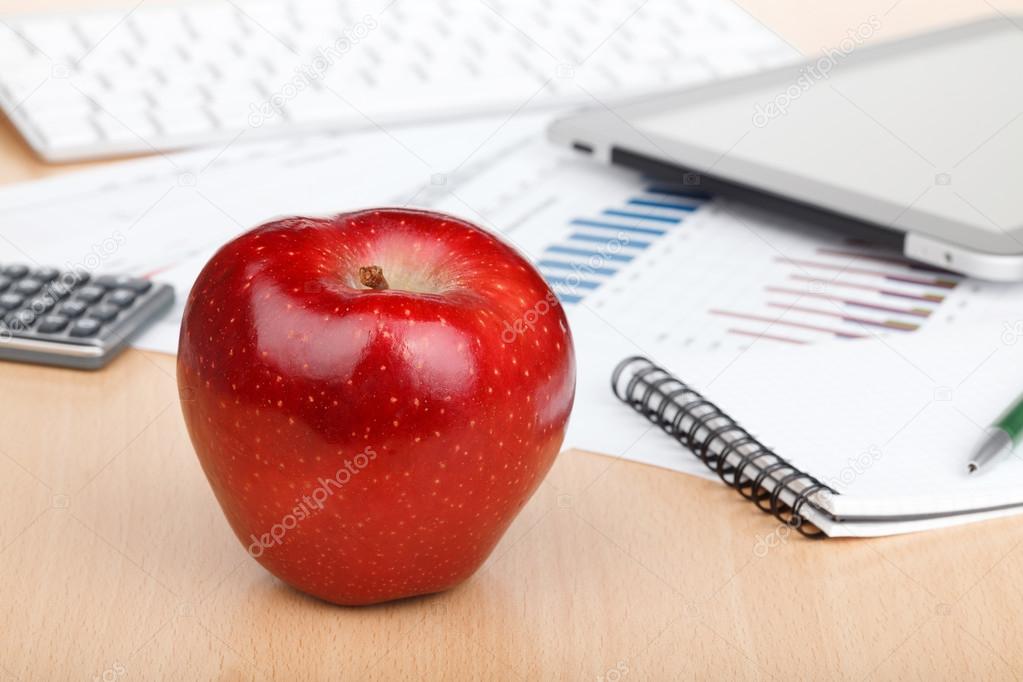 Ripe red apple on workplace