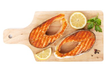limon dilimleri ve üzerinde kesme tahtası bitkiler ile ızgara somon